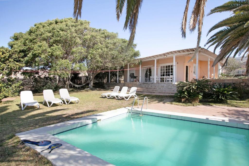 a swimming pool with chairs and a house at Saint Maxime in Adeje