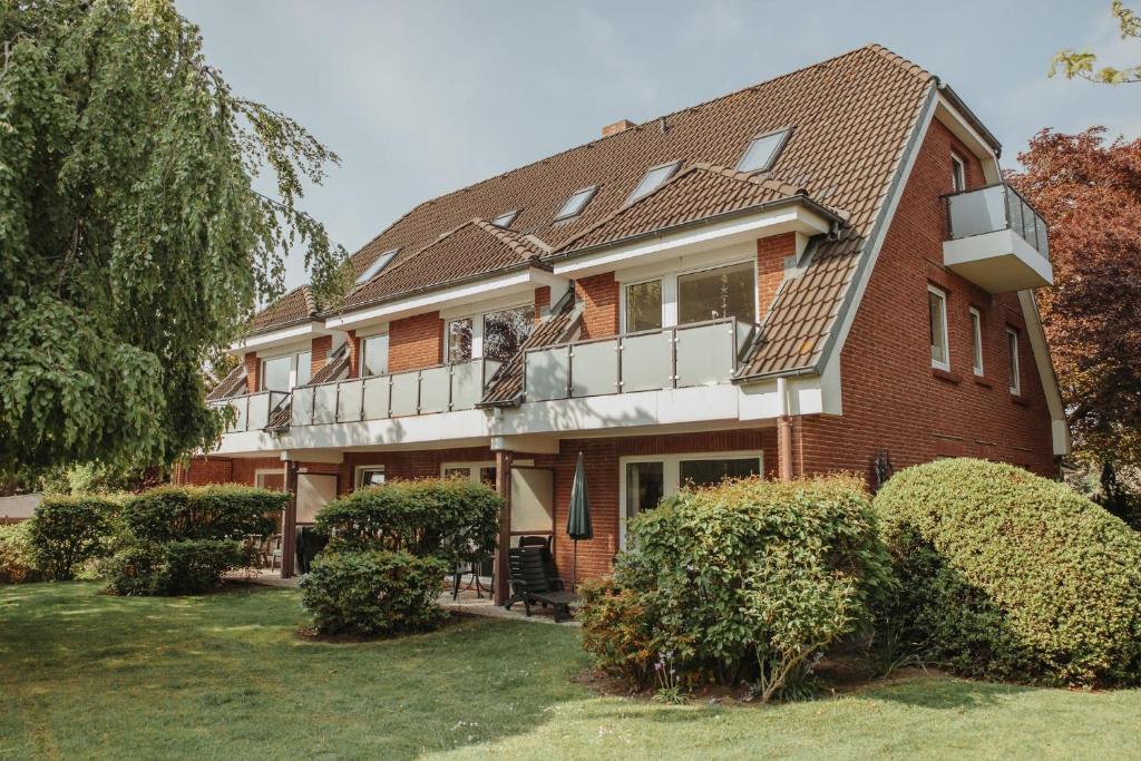a red brick house with a balcony and bushes at Gästehaus Bröcker Wohnung 7 in Büsum