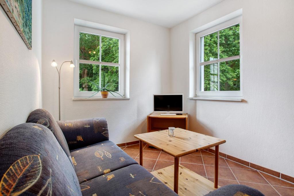 a living room with a couch and a table and two windows at Haus Seeadler Wohnung 11 in Koserow