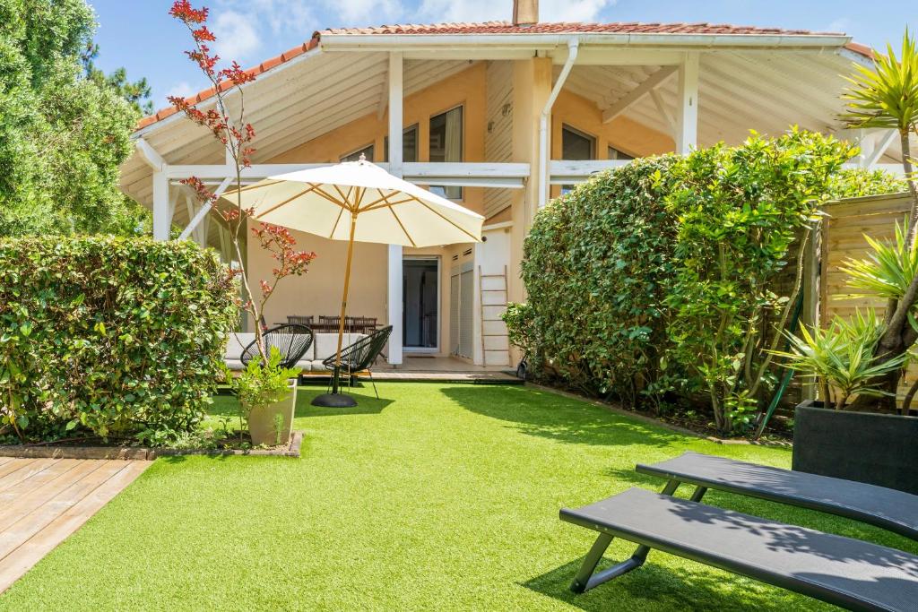 a patio with a bench and an umbrella in a yard at Dune Lodge 2- Capbreton Hossegor - in Capbreton