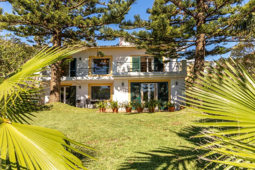 a white house with palm trees in front of it at Villa Echium T1 in Caniço