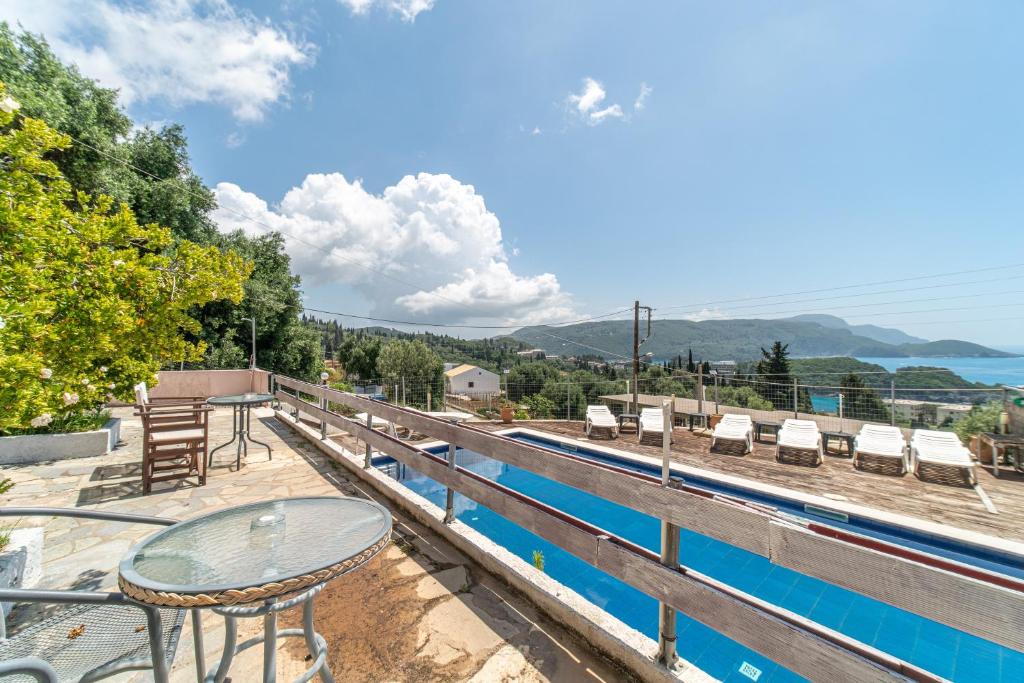 a balcony with a table and chairs and a pool at Spyridoula Studio 13 in Paleokastritsa