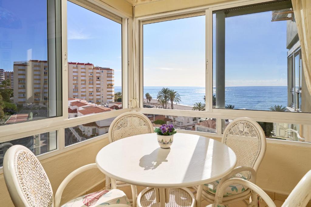 a white table and chairs in a room with windows at Sea Views Centro Internacional A99 in Torrox