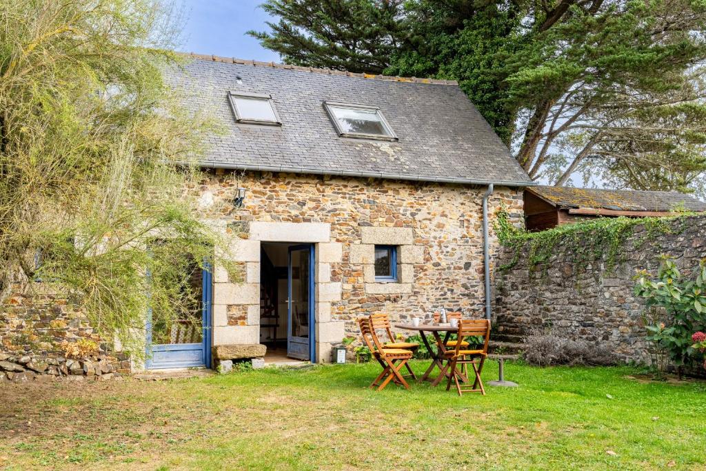 un cottage in pietra con tavolo e sedie nel cortile di Ville Daniel a Pordic
