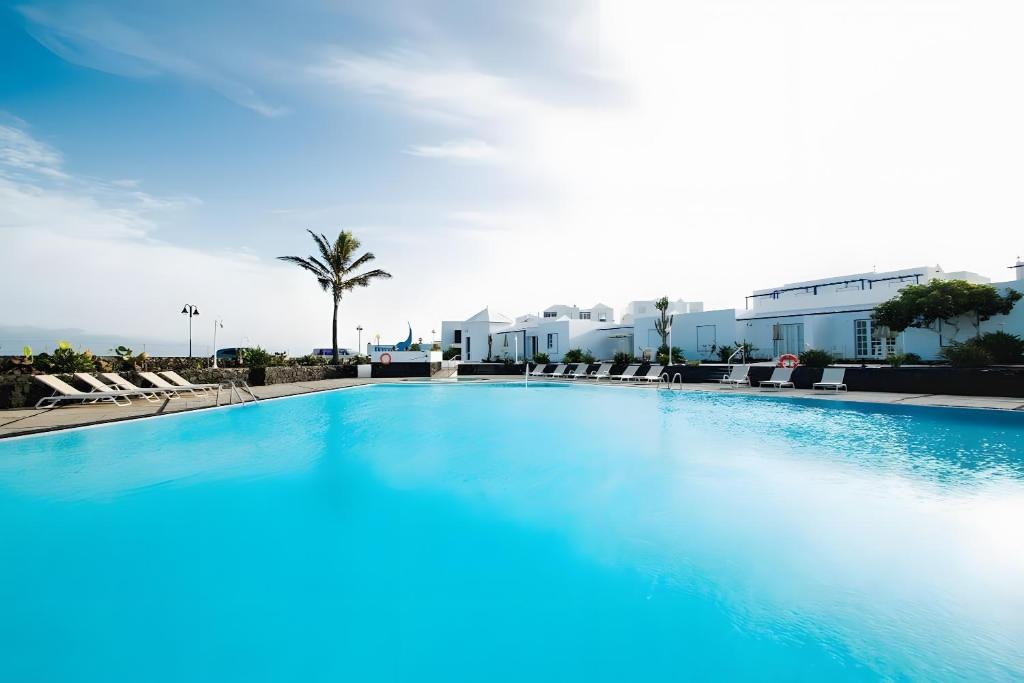 a large swimming pool with chairs and buildings at Bungalow 3 - Caleta Campos in Arrieta