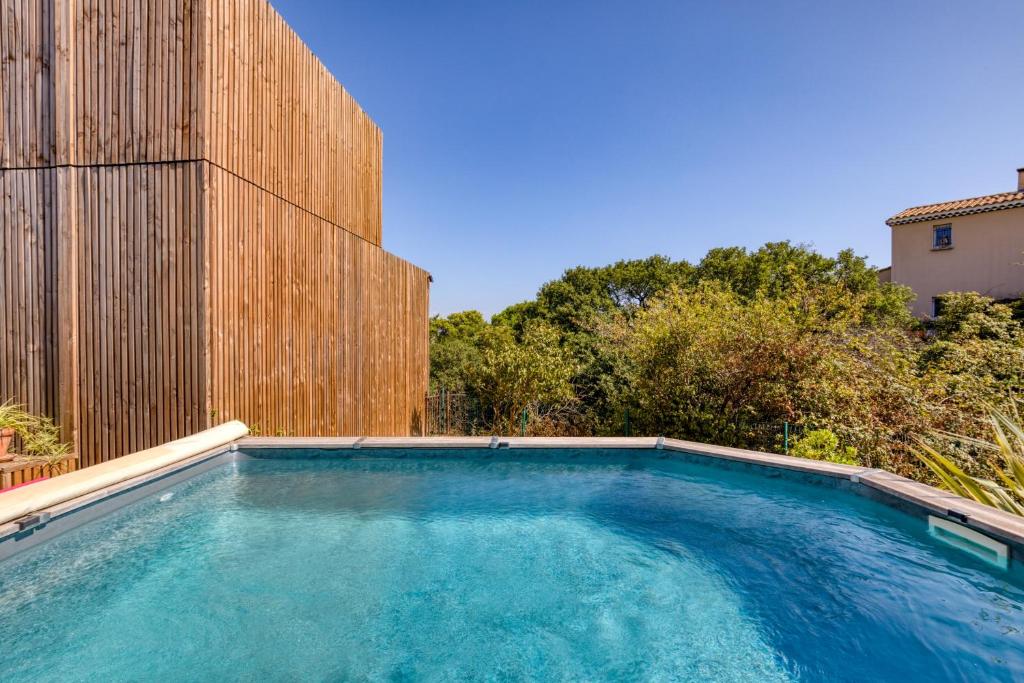 a swimming pool in front of a wooden fence at Maison Greenkub in Générac