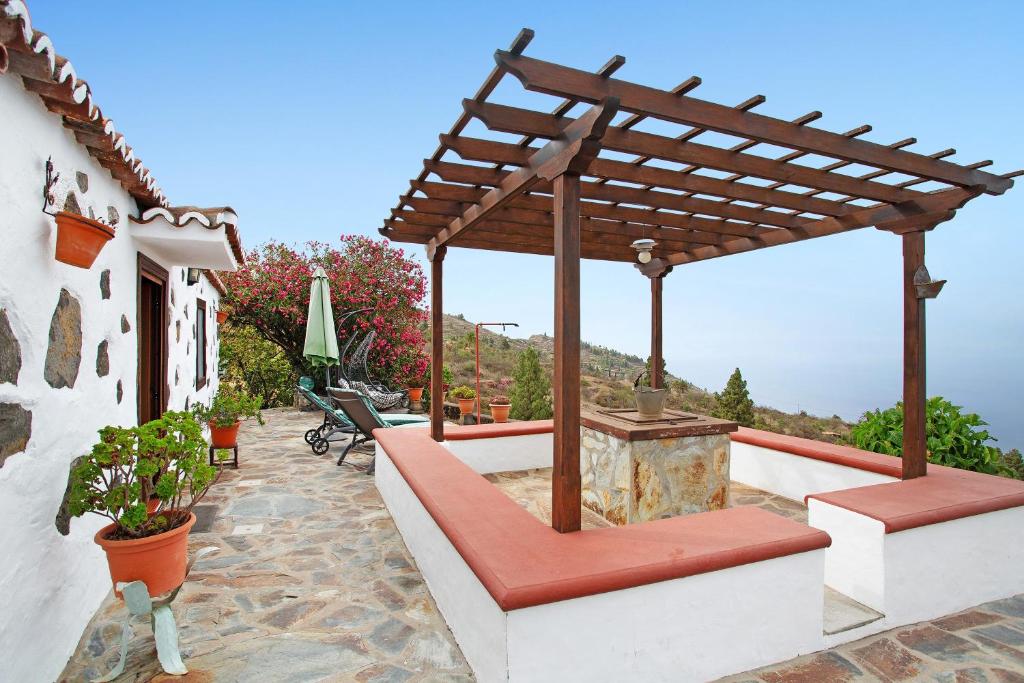 a patio with a wooden pergola and benches at La Chirlaca in Tijarafe