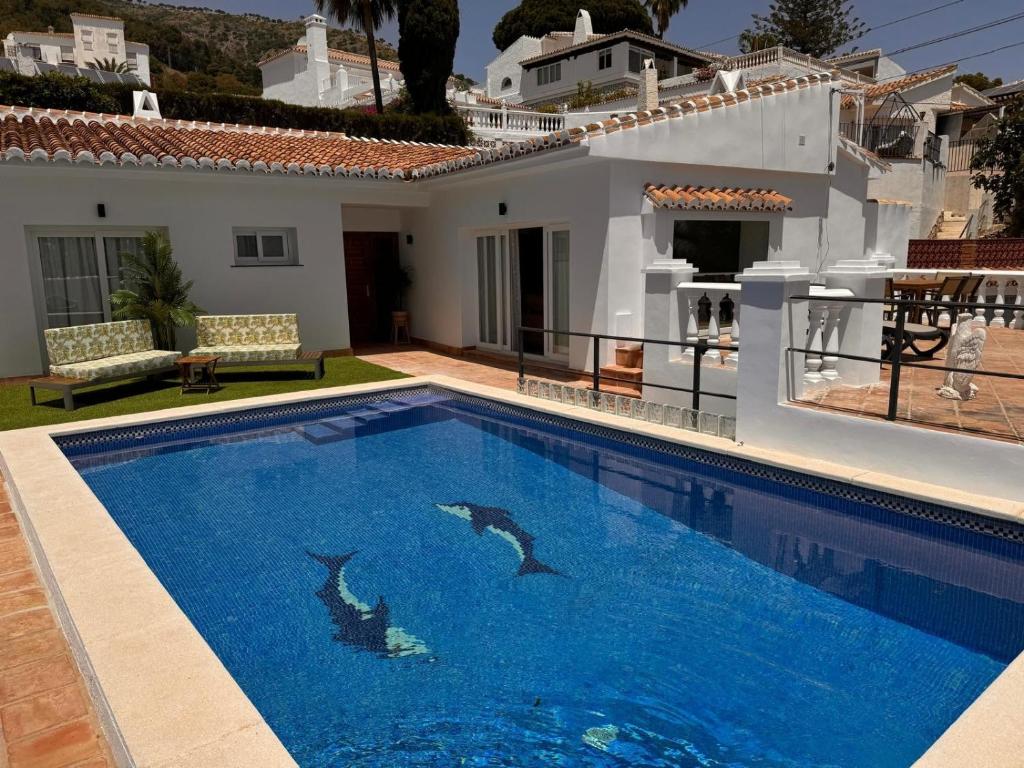 two dolphins swimming in a swimming pool in front of a house at Villa Gracia in Mijas