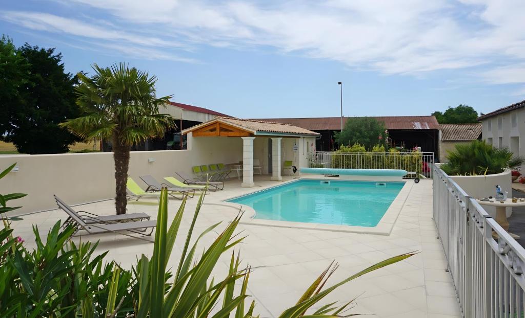 a swimming pool with two chairs and a palm tree at Chambre d'hôtes La Champagne in Sémussac