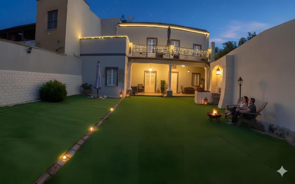 two people sitting on a lawn in front of a house at Luxar Suites and Apartments in Assemini