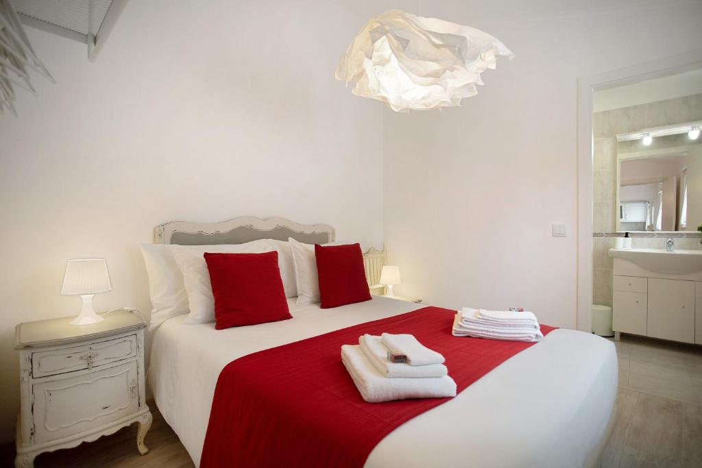 a bedroom with a red and white bed with towels on it at Páteo da Várzea 5 in Colares