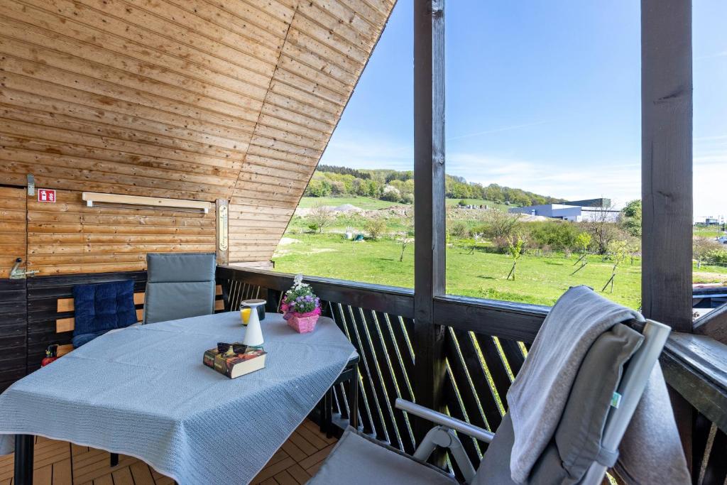 a table on a balcony with a view of a field at Ferienwohnung im Elsetal in Plettenberg