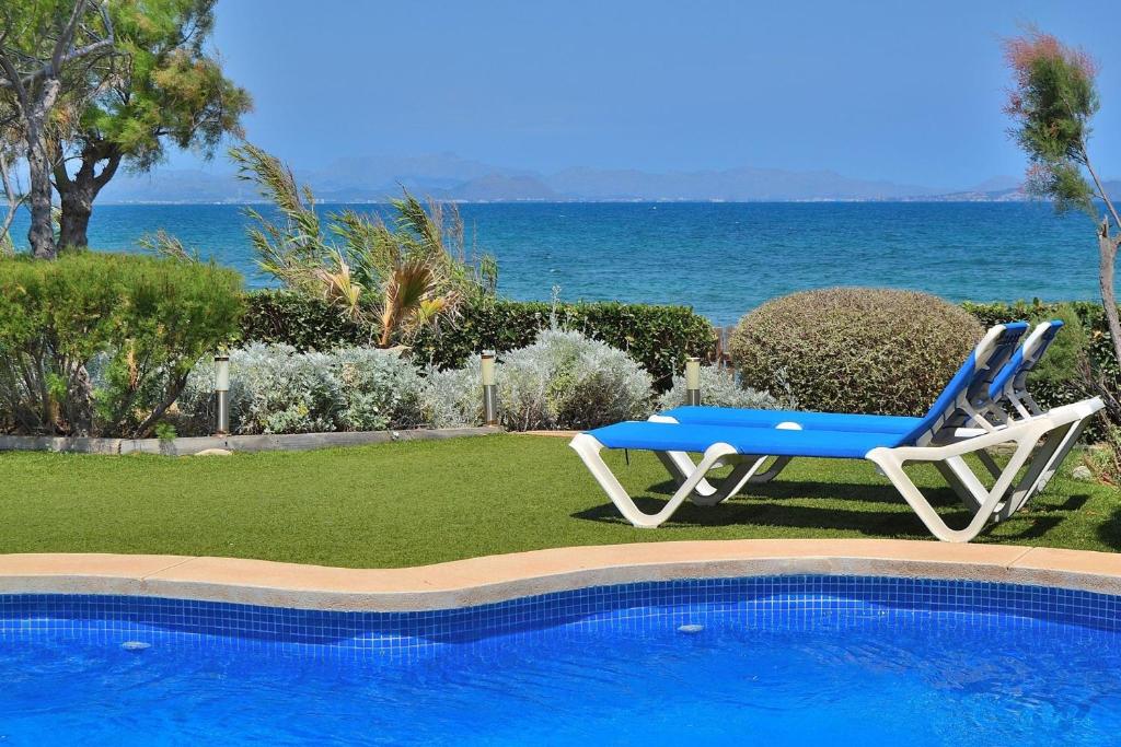 a blue and white chair sitting next to a swimming pool at Embat in Colonia de Sant Pere
