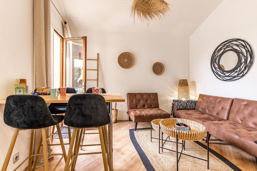 a living room with a couch and a table and chairs at Maisonnette Biscarosse in Biscarrosse
