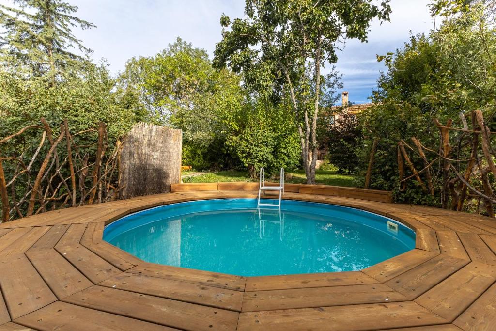 a pool with a wooden deck and a swimming pool with a water feature at Dalt La Figuera in La Higuera