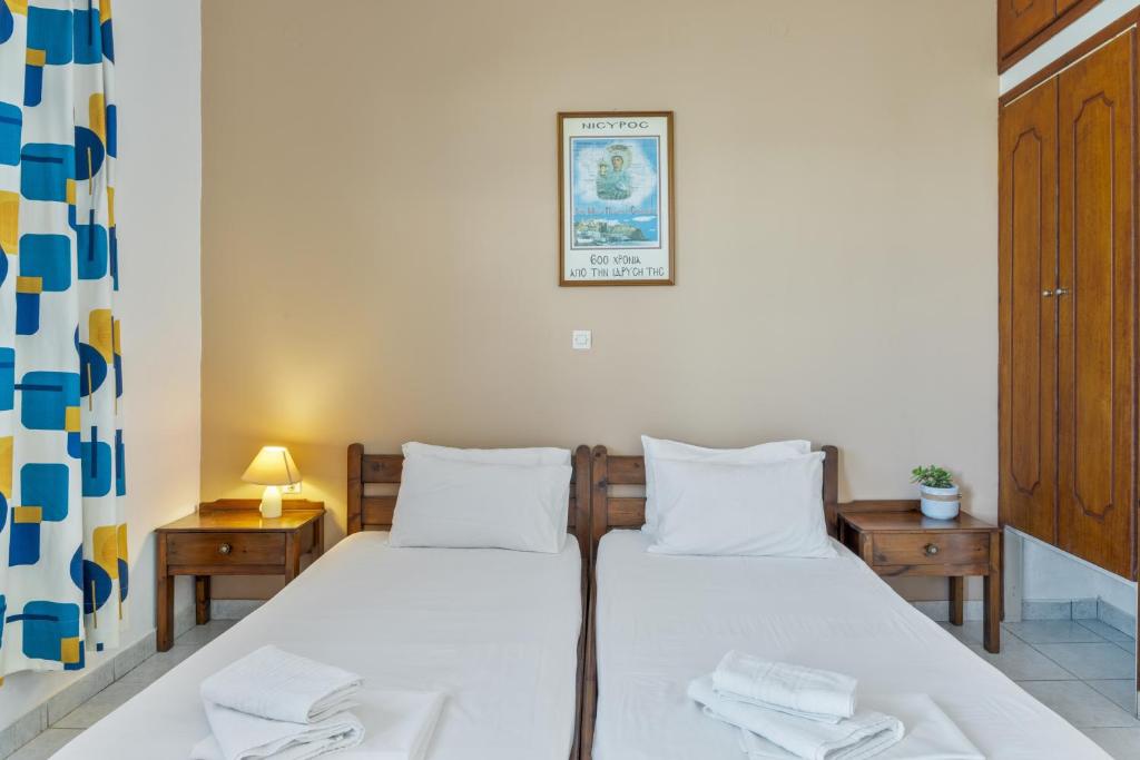 a bedroom with two beds with white sheets and two tables at Frantzis Studio 6 Nisyros Island in Páloi