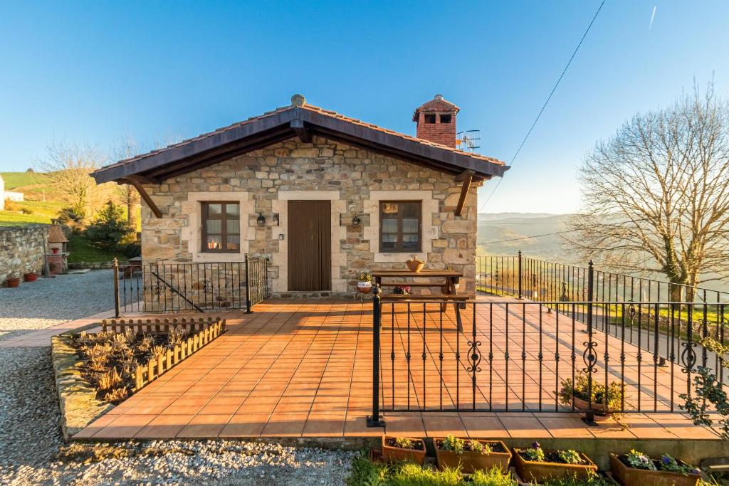a small stone house with a black fence at Apartamento Juntana 2 in Villacarriedo