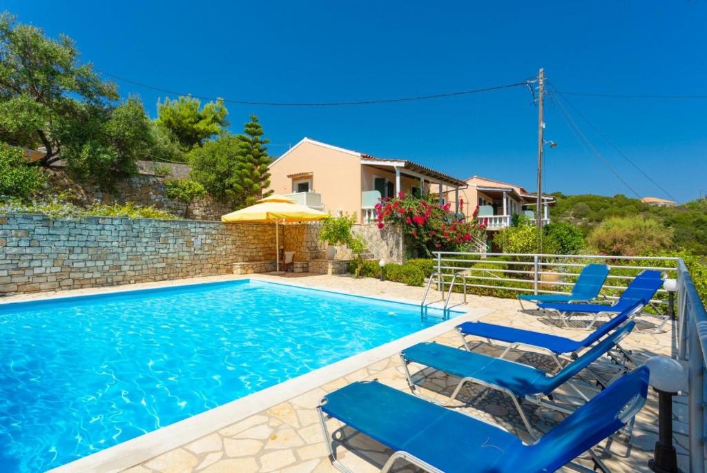 a swimming pool with blue chairs and a house at Dolphin villa 1 in Gaios