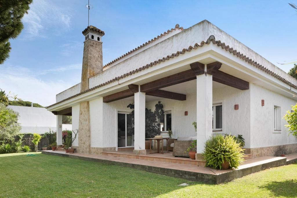 a white house with a porch and a grass yard at Sol, playa y diversion en Roche in Roche