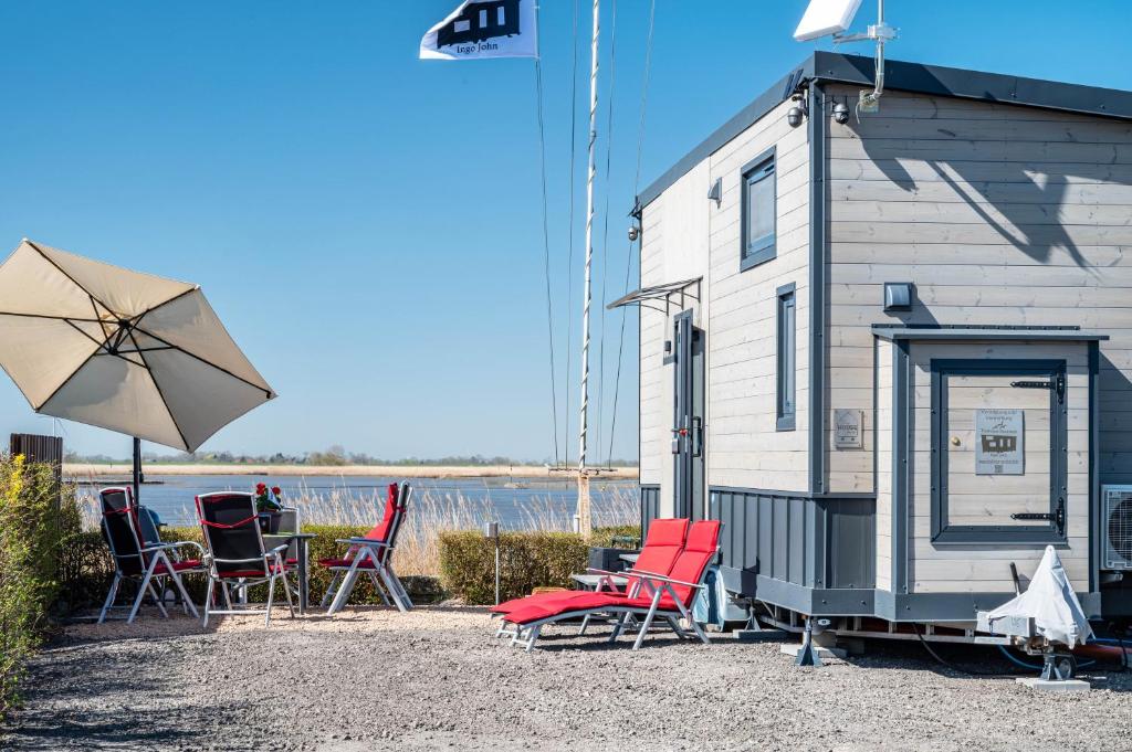 eine Gruppe von Stühlen und ein Sonnenschirm neben einem Gebäude in der Unterkunft Tiny House Ingo John 'Shadow' in Sandstedt