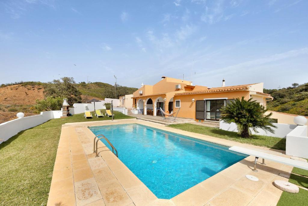 a villa with a swimming pool in front of a house at Vila Portimão T5 com Piscina in Portimão