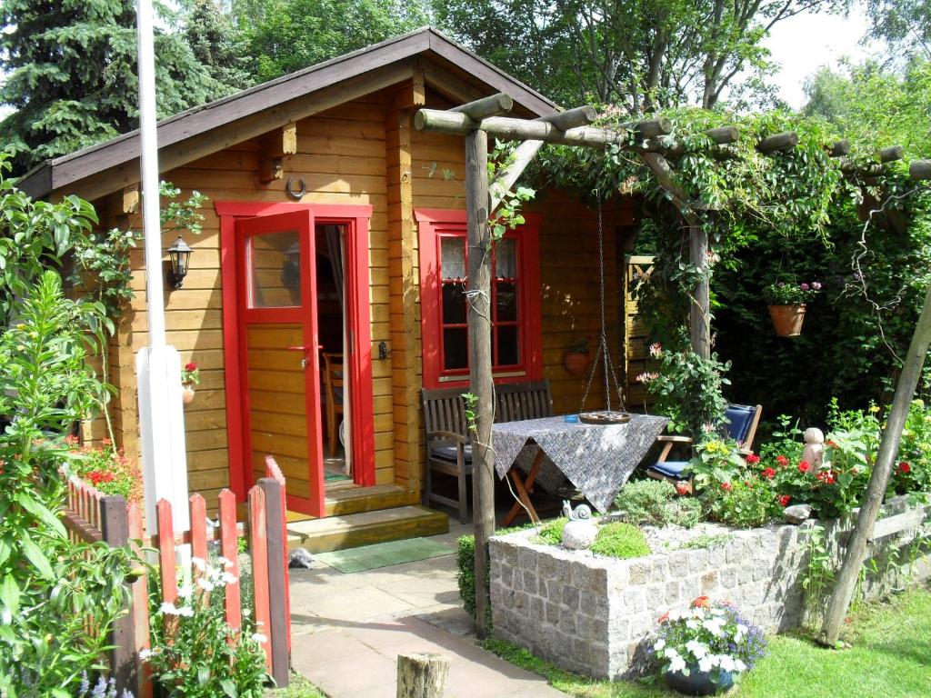 a small cabin with a red door in a garden at Privatzimmer R und C Lohnherr in Lehnin