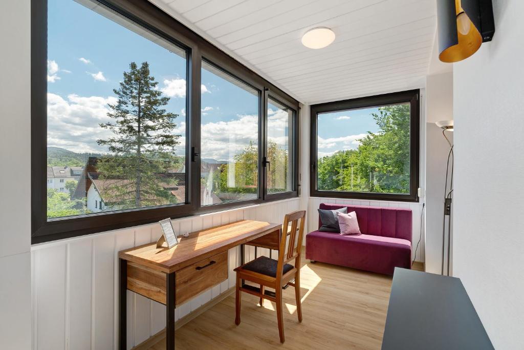 a room with windows and a table and a purple couch at Modern eingerichtetes Apartment in Achern