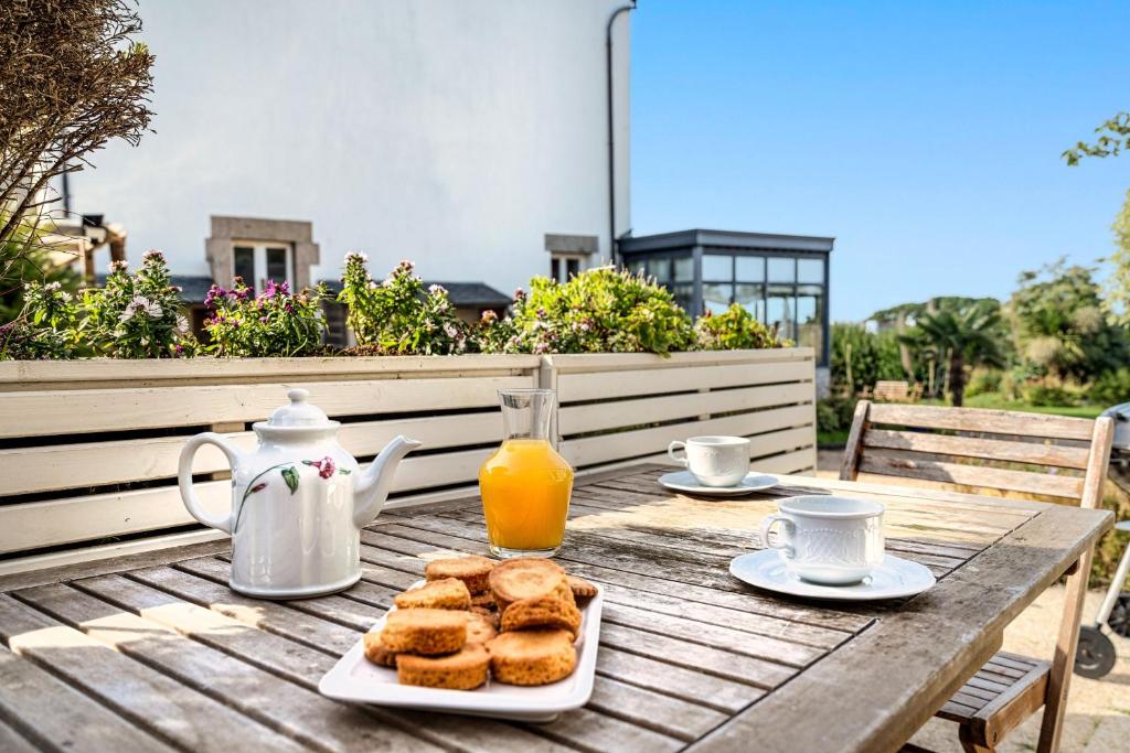 a wooden table with a breakfast of biscuits and orange juice at La Maison du Gardien in Portsall