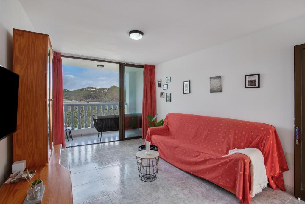 a living room with a red couch and a balcony at El Granero in Moya