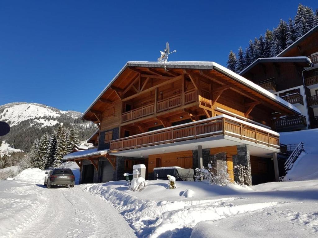 a building in the snow with a car in front at Chalet Clemalou 14-15 Personnes in Châtel