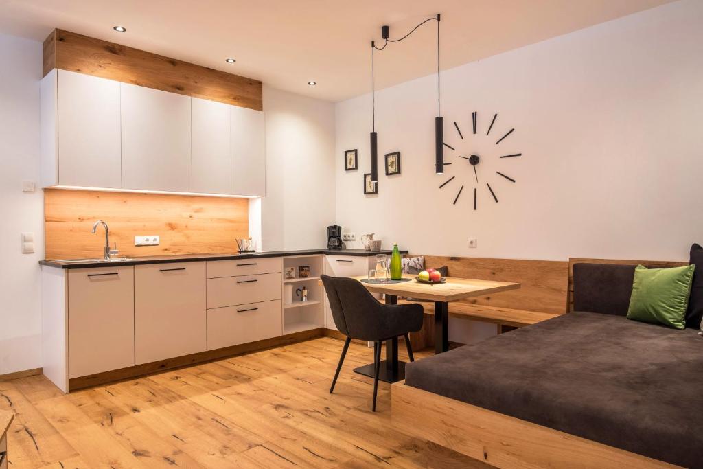 a kitchen with a table and a kitchen with a clock on the wall at Luisl Hof - Apartment Herbae in Cornaiano