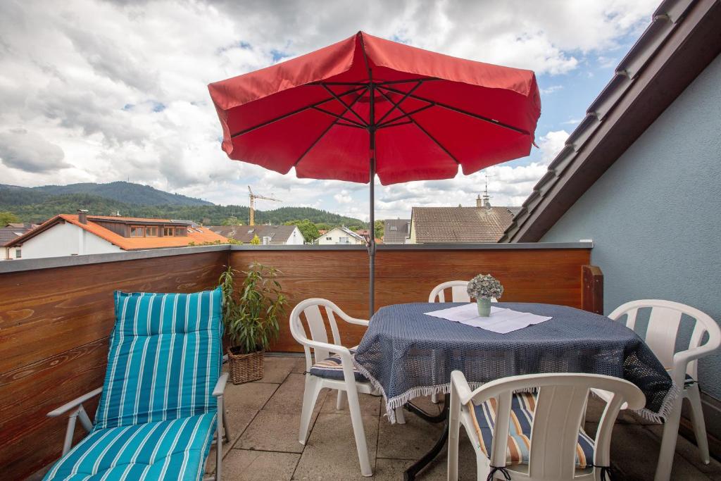 a red umbrella on a balcony with a table and chairs at Ferienwohnung Thelen in Wallbach