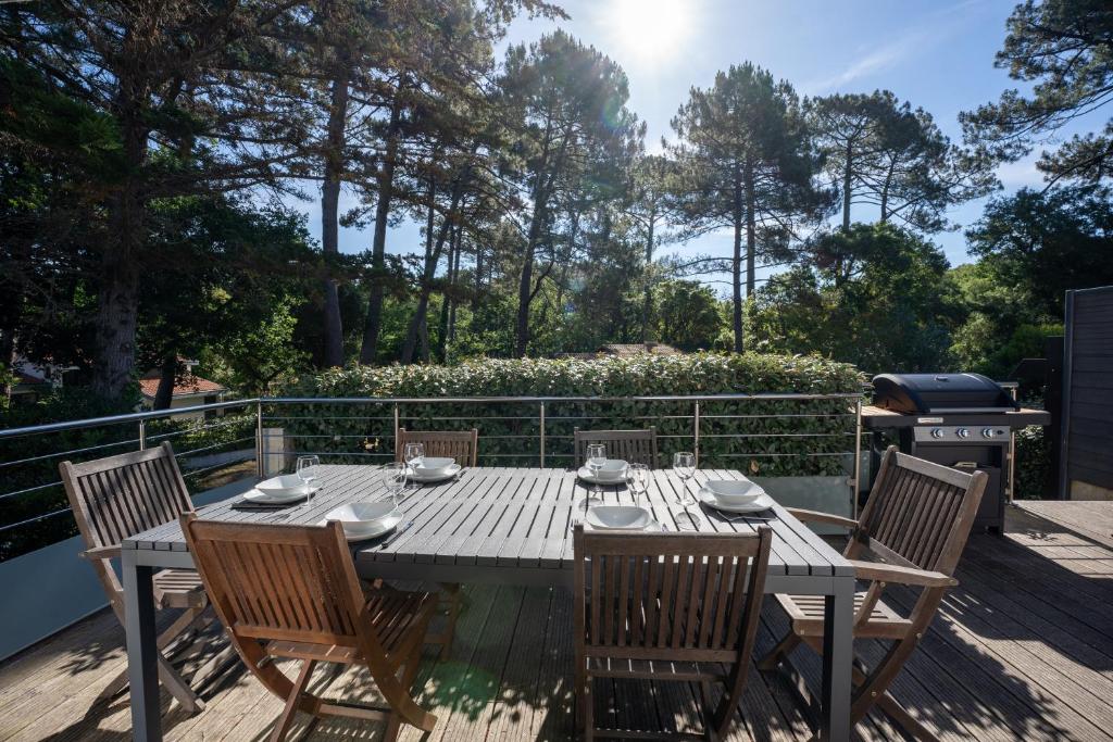 a wooden table and chairs on a deck with a grill at Seignosse Le Penon, maison Patio in Seignosse