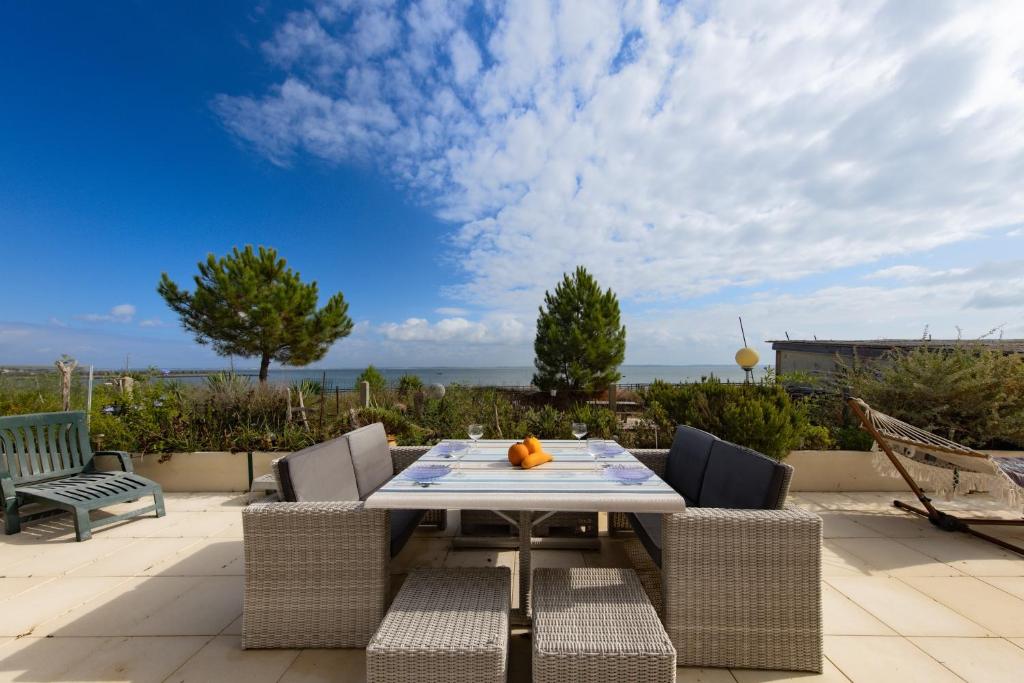 a table and chairs on a patio with a view of the ocean at Maison Les Pieds Dans L'eau in Le Verdon-sur-Mer