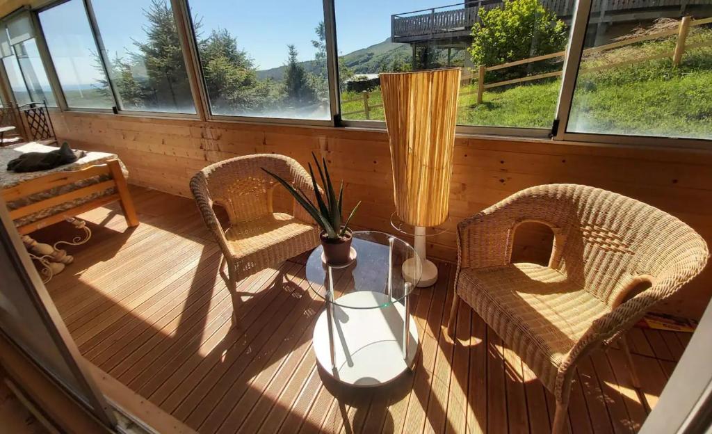 a porch with two chairs and a table with a vase at Superbe appartement avec loggia in Super Besse