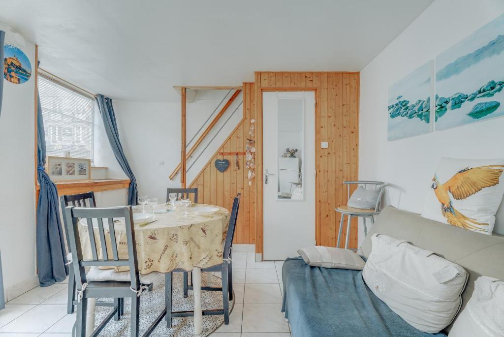 a dining room with a table and a couch at Maison proche Mont St Michel in Pontorson