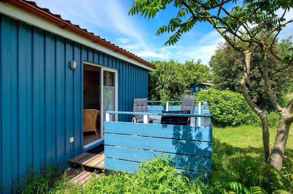 a blue house with a deck in a yard at Möve Aba Bungalow 60 in Rerik