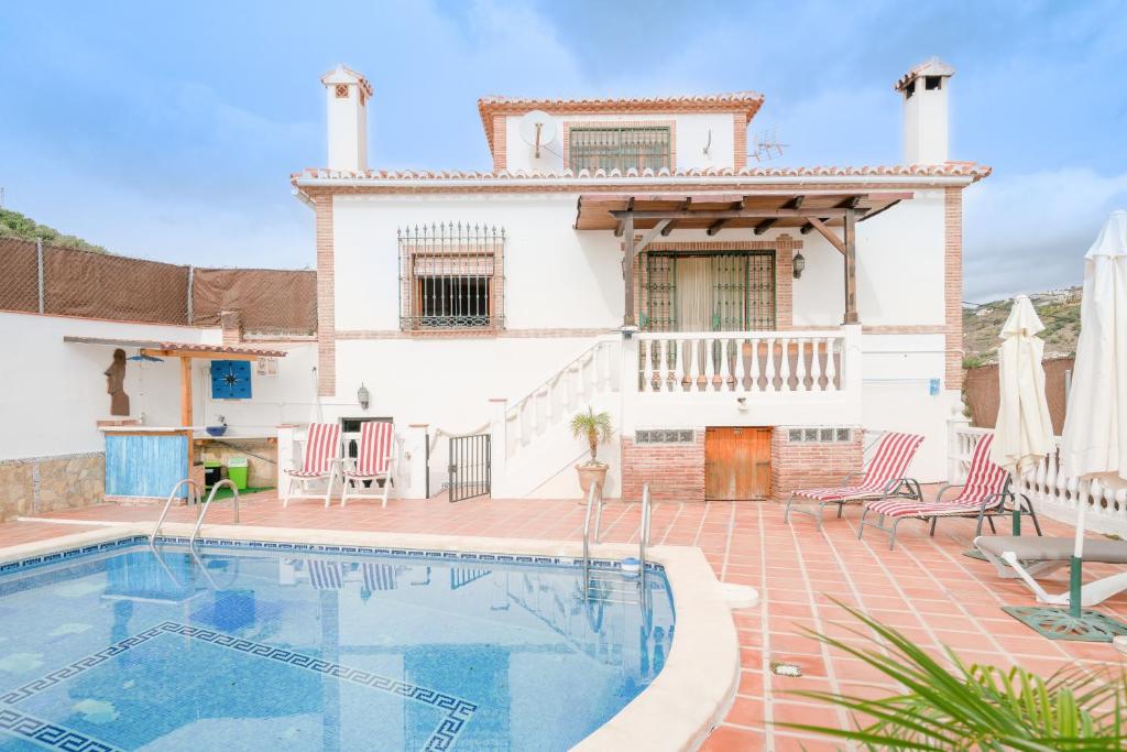 a villa with a swimming pool in front of a house at Villa Padial in Torrox