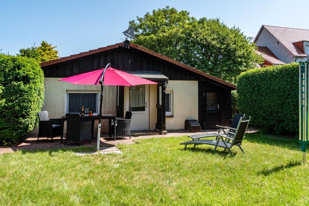 a patio with a table and an umbrella in the yard at Ferienhaus Strandfloh in Wangerooge