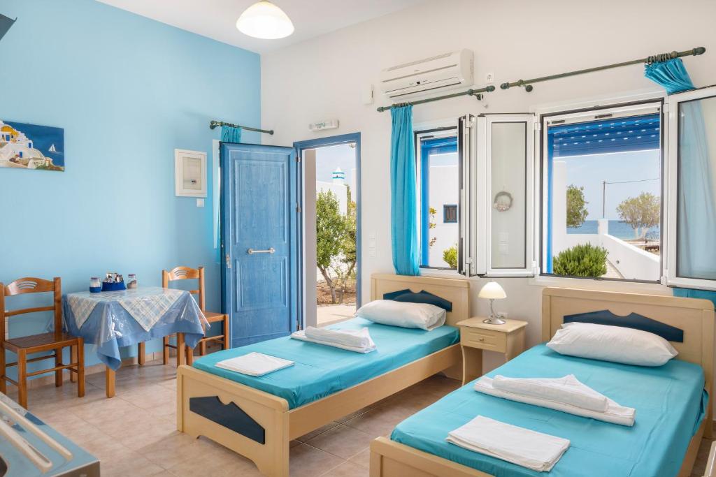 a room with two beds and a table and chairs at Studios Ninemia Serifos 1 in Livadi