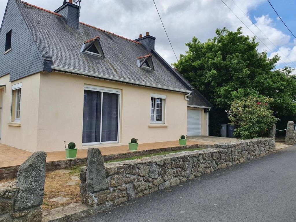 a house with a stone wall in front of it at Gîte de Locmousteru in Moustéru