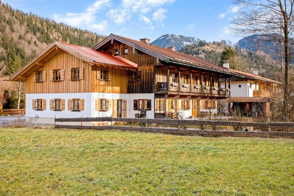 a large wooden house with a field in front of it at Ferienwohnung Uferweg in Fischbachau