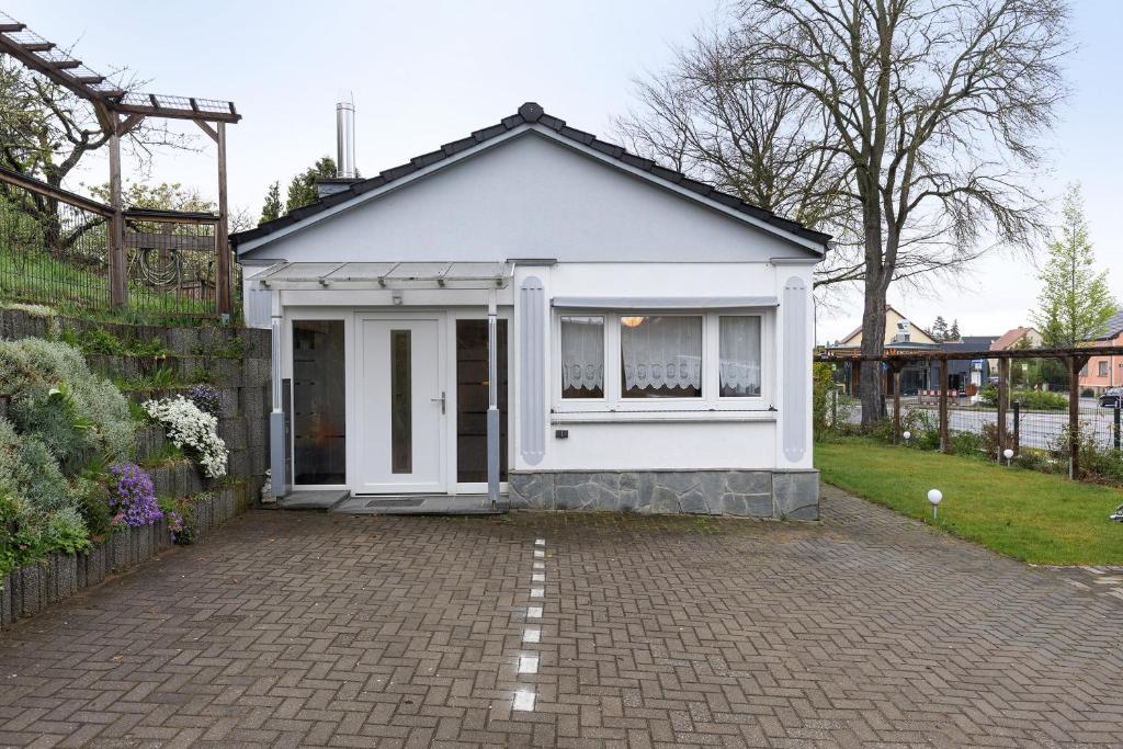 a small white house with a brick driveway at Ferienhaus Günther in Werder