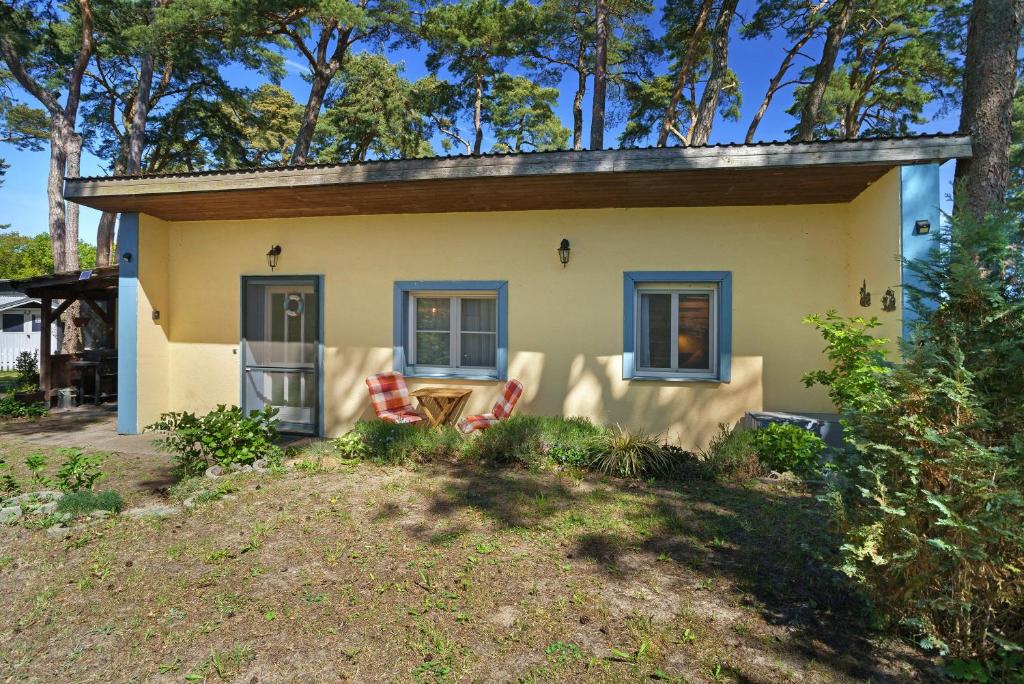 a small yellow house with two chairs in front of it at Bungalow Karsten in Kamminke