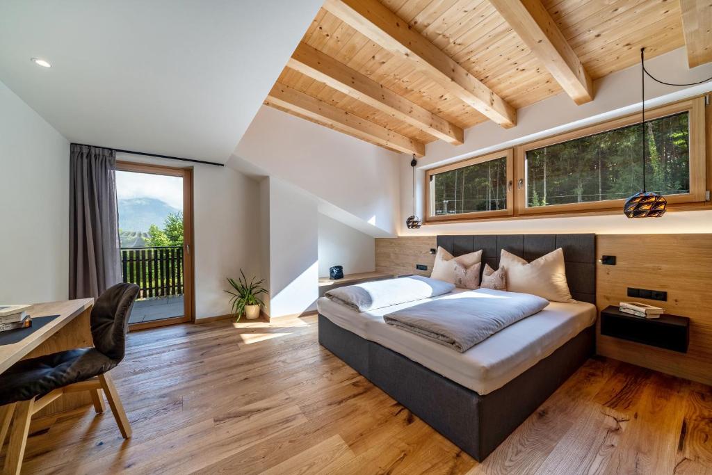 a bedroom with a bed and a desk and windows at Wiesgut Ferienwohnung Gala in Tesimo