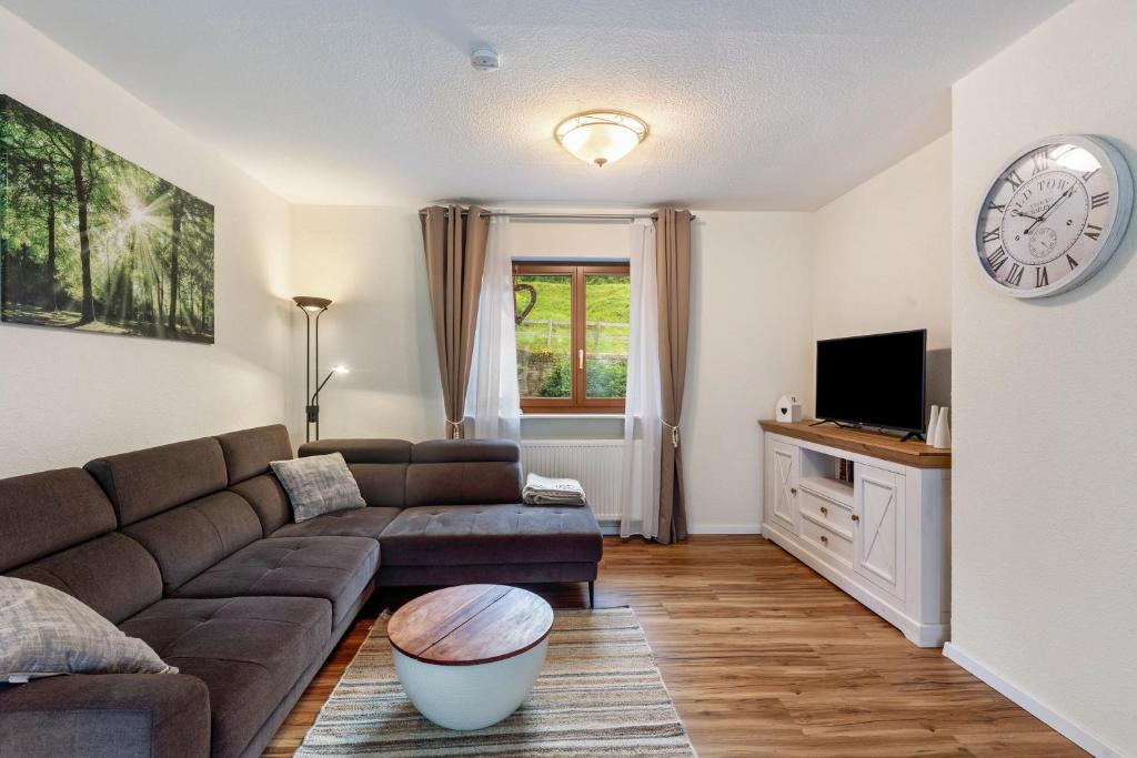 a living room with a couch and a clock on the wall at Hof Helmenhube 1 in Oberzent