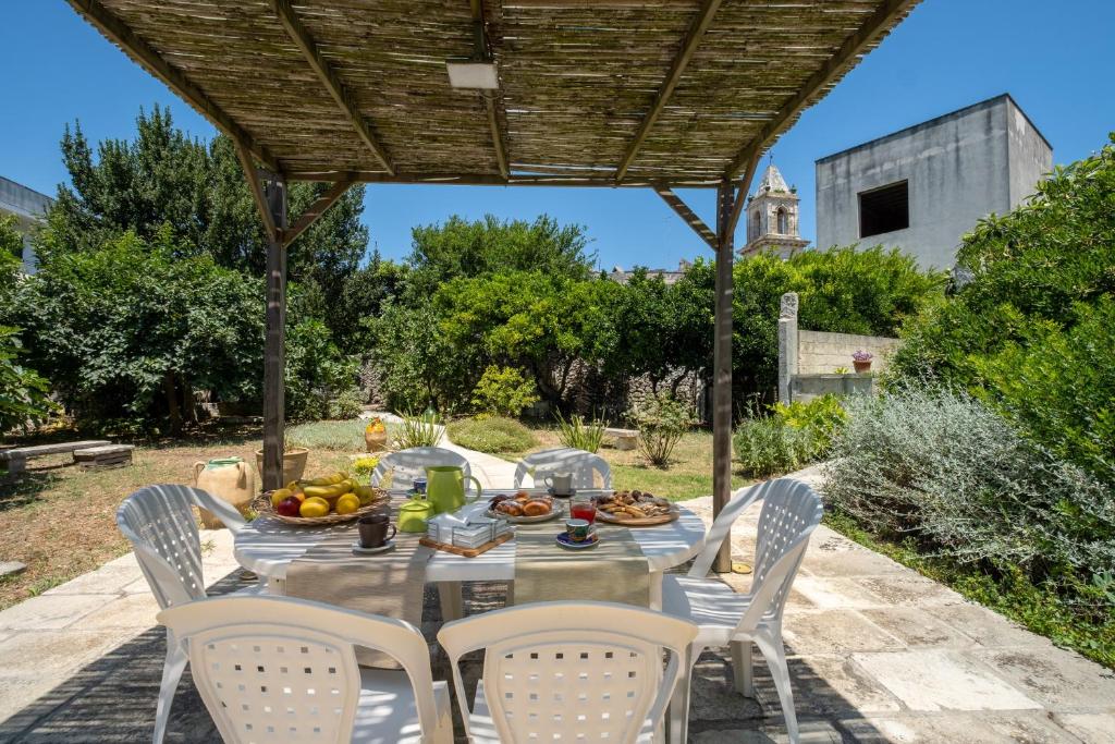 a table and chairs under a wooden pergola at La dimora Elia' in Muro Leccese