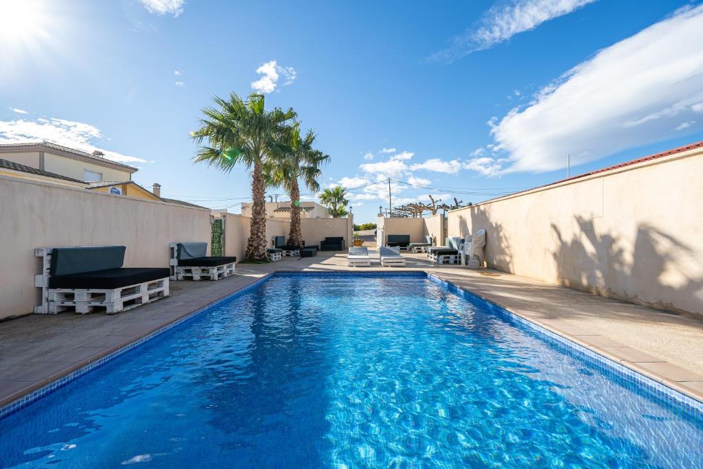 a swimming pool with chairs and palm trees next to a building at La Marquesa in Camarles