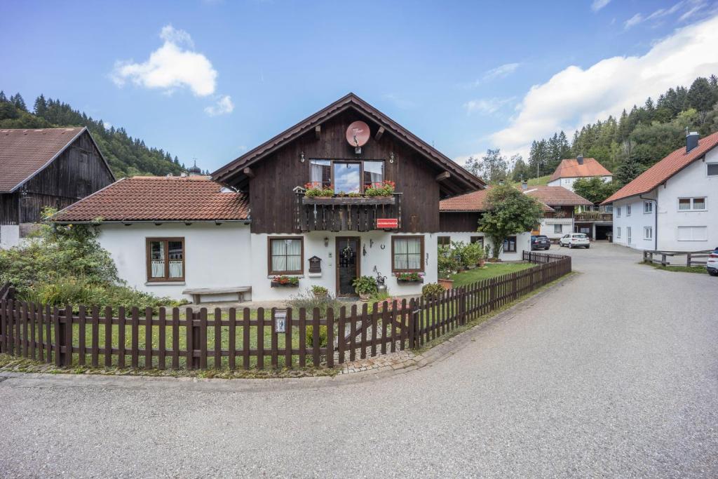 a house with a wooden fence in a village at Ferienwohnung im Haus Kreuzthal in Buchenberg