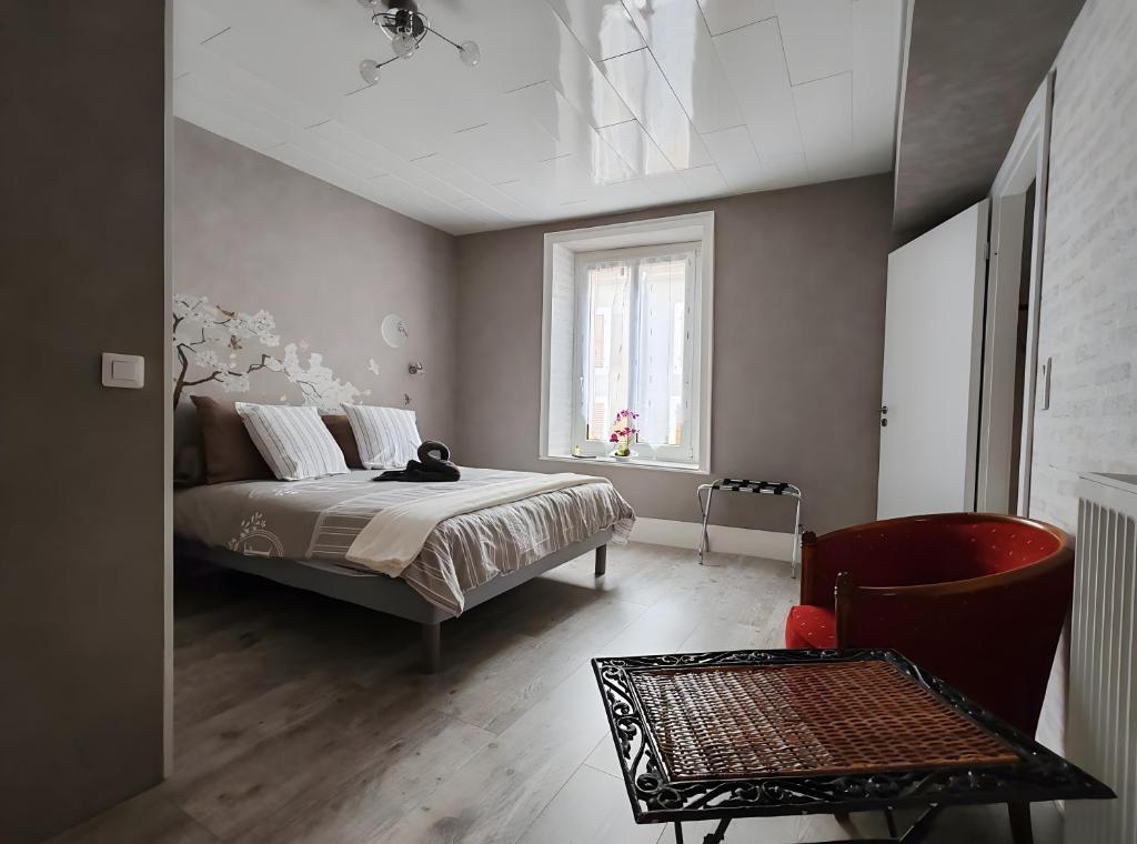 a bedroom with a bed and a chair and a window at Domaine Du Hêtre - Meublé T2 in Bains-les-Bains